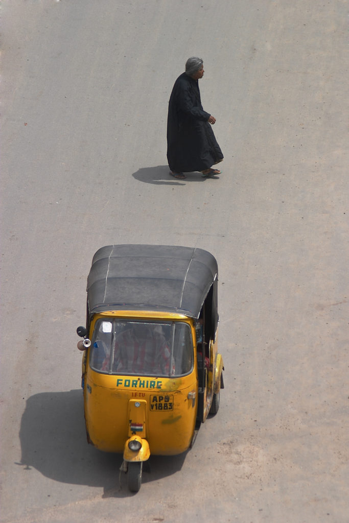 Old muslim lady crossing the street in the busy part of old Hyderabad, India